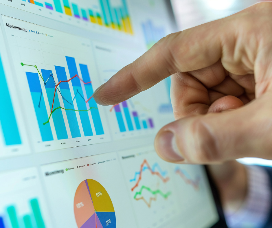 A finger points to a screen filled with colorful charts and graphs.