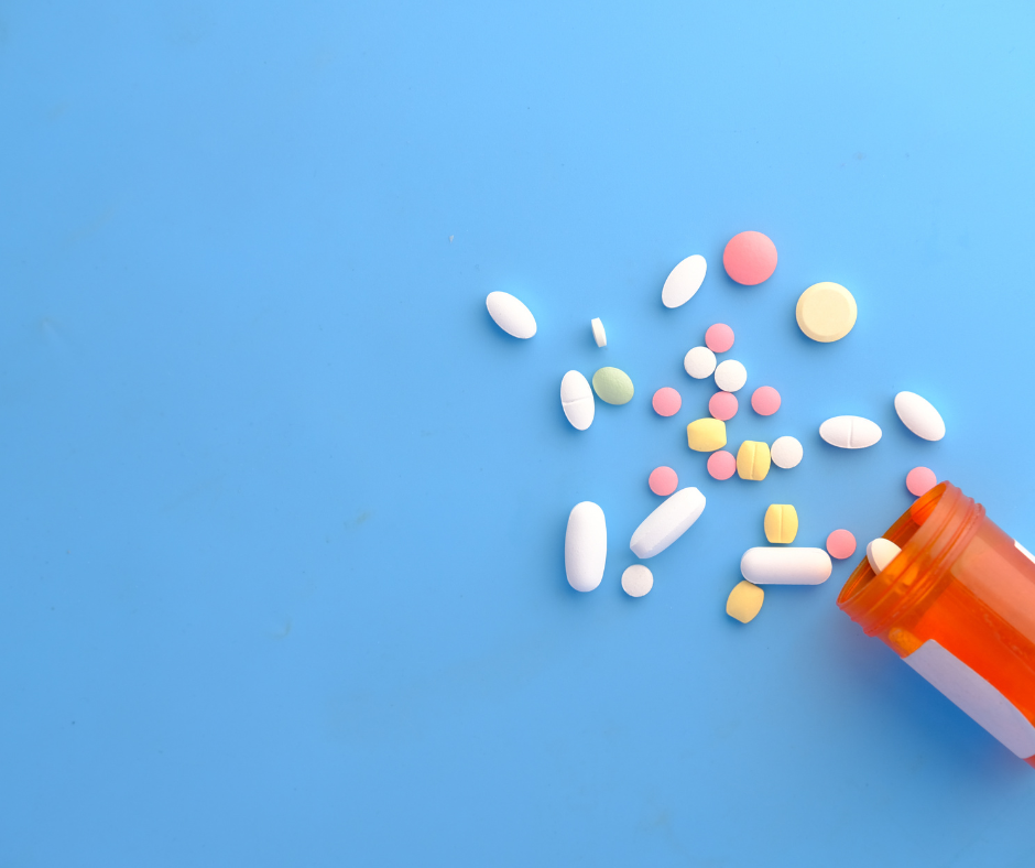 Prescription pill bottle with various size and colored pills spilling out of it. 