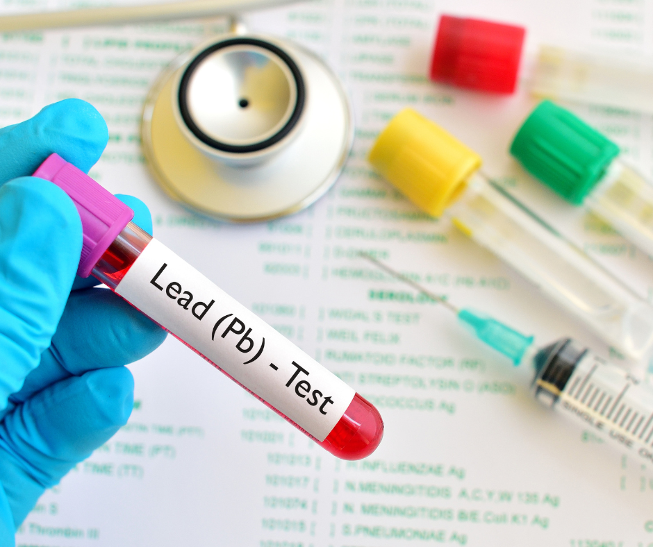 Colorful test tube with red liquid labelled with "Lead (Pb) - Test" next to a needle, 3 test tubes with varying colors, and a stethoscope on top of a paper with green text.