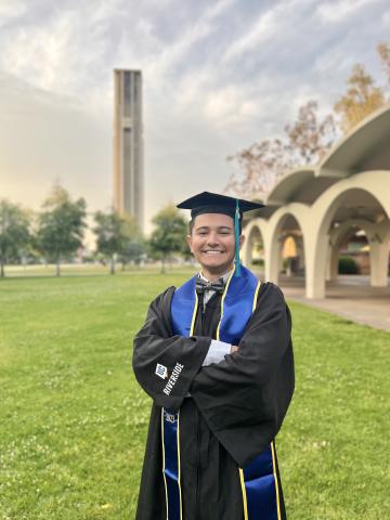 Person wearing graduation regalia in front of a green lawn