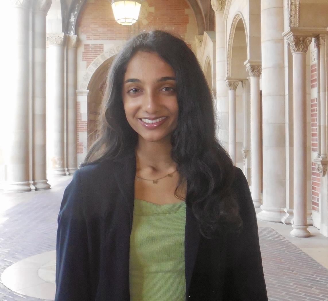 Woman with black hair in front of a hallway
