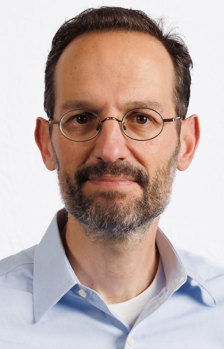 Man with brown hair and glasses wearing a blue shirt
